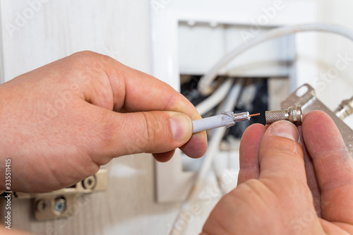 Worker inserts connector of a TV antenna coaxial cable.