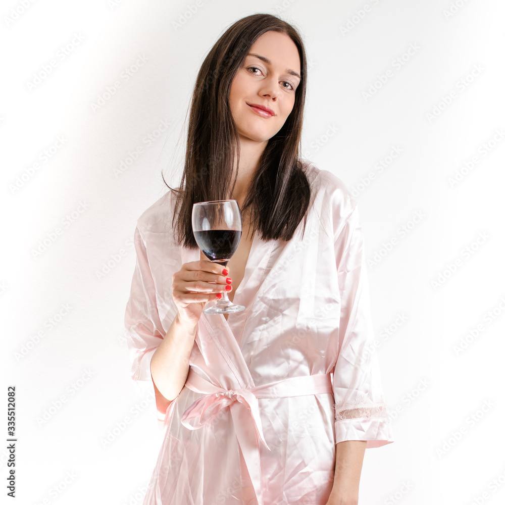 Attractive young brunette woman wearing a pink nightgown, holding a class of red wine smiling Attractive young brunette woman wearing a pink nightgown, holding a class of red wine smiling