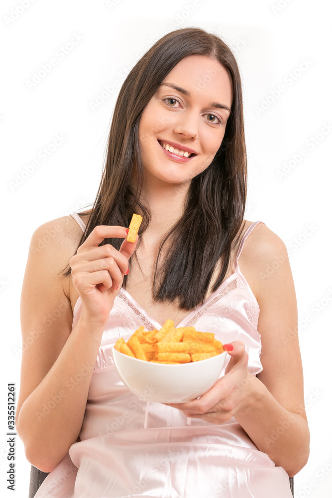 Attractive young brunette woman wearing a pink nightgown, having a bowl of potato chips Attractive young brunette woman wearing a pink nightgown, having a bowl of potato chips