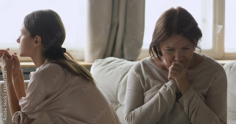 Depressed mature older mom feeling unhappy after conflict with grown up daughter, thinking of family troubles. Stubborn young woman avoiding talking to sensitive stressed mature middle aged mom. Depressed mature older mom feeling unhappy after conflict with grown up daughter, thinking of family troubles. Stubborn young woman avoiding talking to sensitive stressed mature middle aged mom.