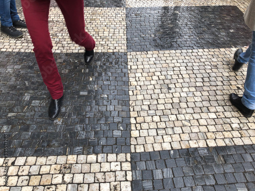 legs walking on a black and white cobblestone street in Prague