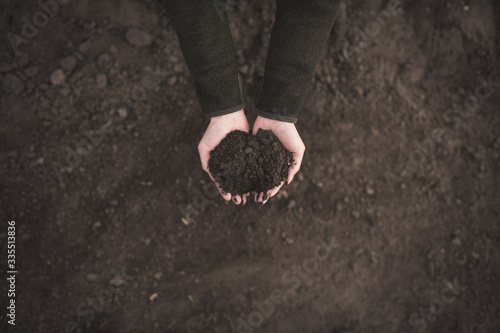 Photos Female hands pouring a black soil in the field