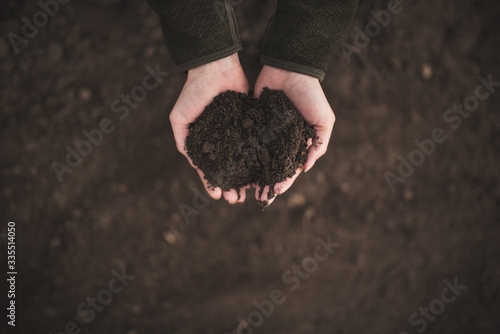 Tableau sur toile Female hands pouring a black soil in the field