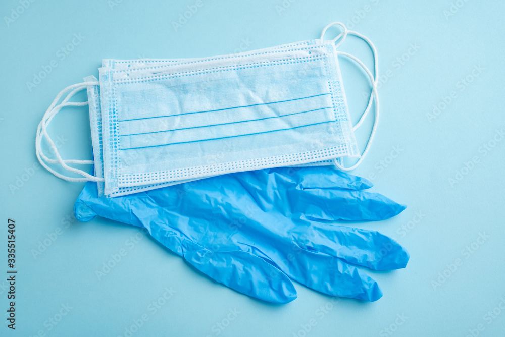 Disposable medical mask and gloves on light blue background Disposable medical mask and gloves on light blue background