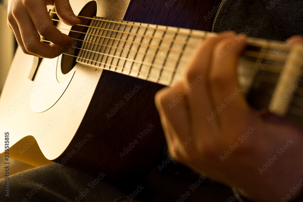 Fototapeta premium Man plays the guitar with warm light close up