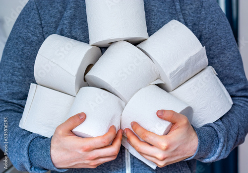 Man holds lots of toilet paper rolls
