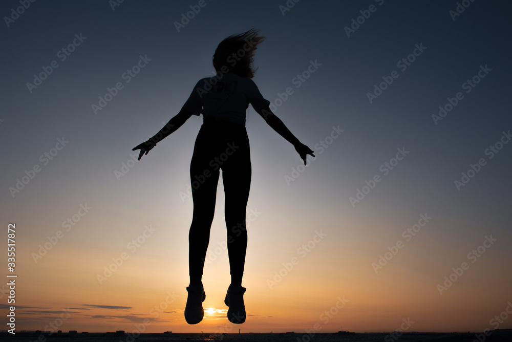 Fototapeta premium silhouette of a jumping girl on a background of dawn