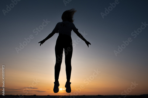 silhouette of a jumping girl on a background of dawn