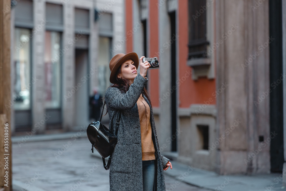 Fototapeta premium Beautiful girl tourist walks and takes pictures of the building.