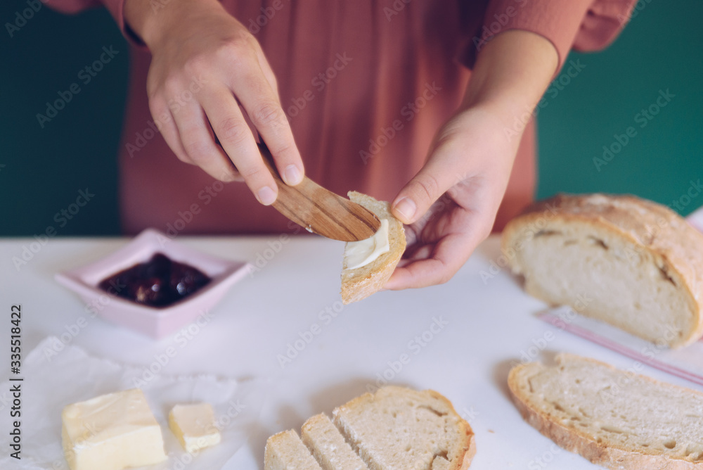 Womans hand spreads butter on homemade bread Womans hand spreads butter on homemade bread