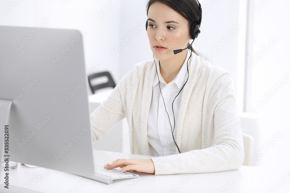 Call center. Casual dressed woman sitting in headset at customer service office. Group of operators at work. Business concept Call center. Casual dressed woman sitting in headset at customer service office. Group of operators at work. Business concept