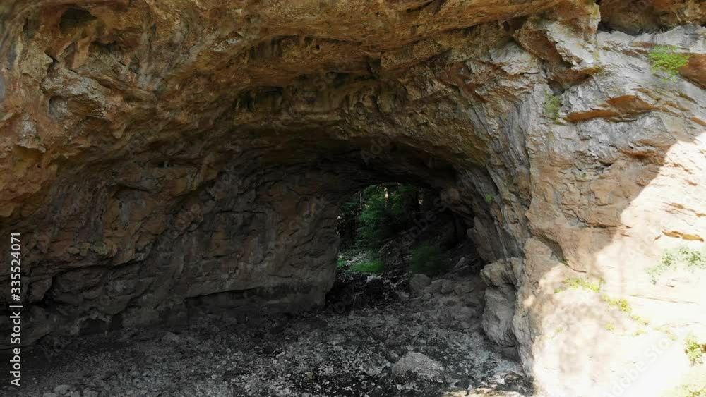 Aerial drone backward shot inside dark narrow rock underpass on sunny day Aerial drone backward shot inside dark narrow rock underpass on sunny day