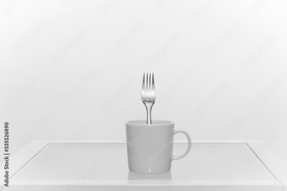 White coffee cup with a fork inside, all white White coffee cup with a fork inside, all white