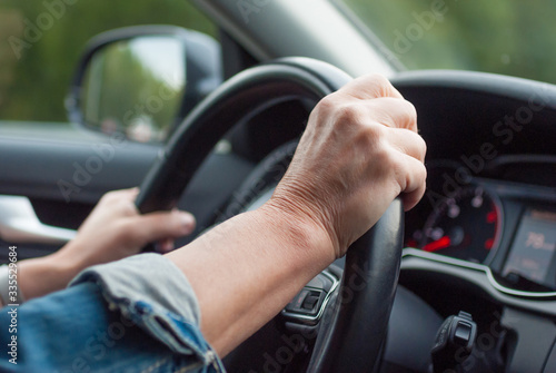Fototapet Middle aged woman driving car. Hands holding a steering wheel.