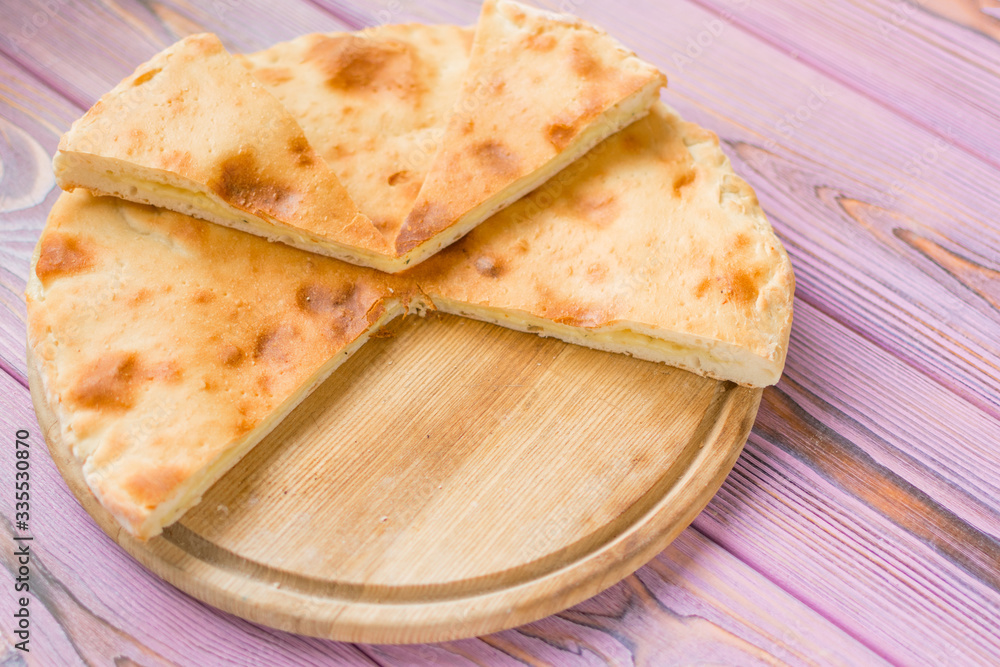 Pie with cheese on a wooden pink background. Khachapuri - flat cake with cheese. Pie with cheese on a wooden pink background. Khachapuri - flat cake with cheese.
