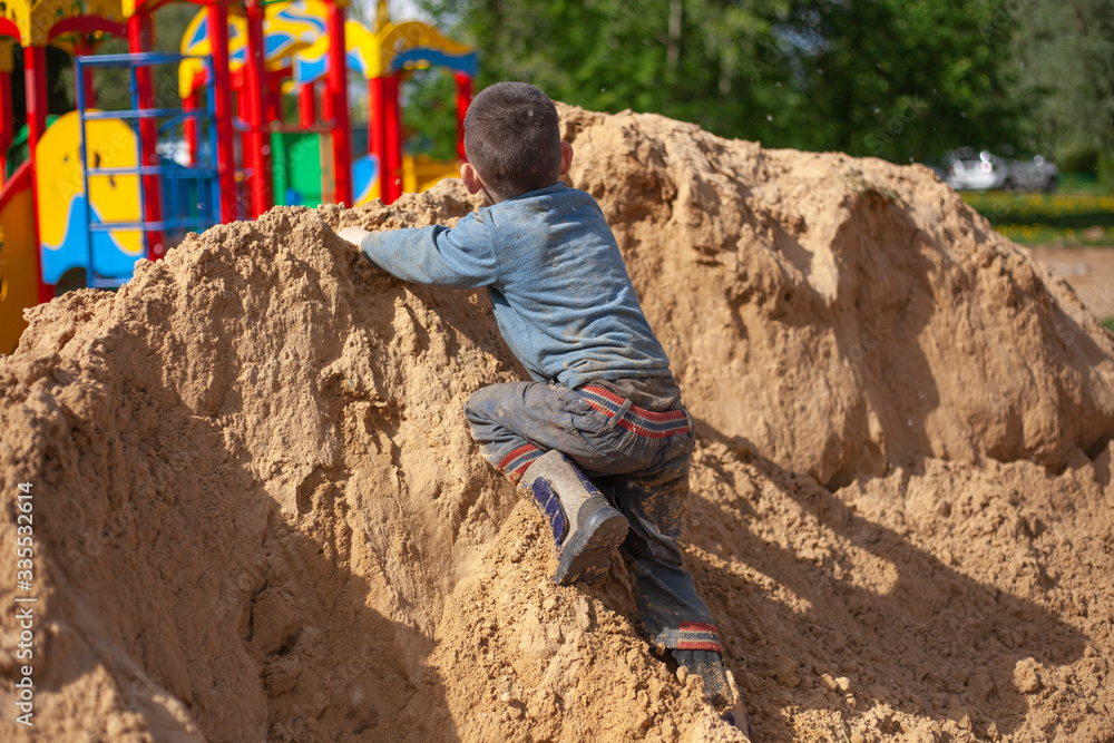 A child falls from a mountain of sand. A child falls from a mountain of sand.