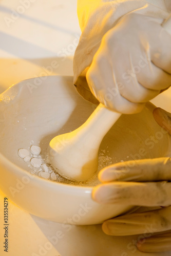 A chemist crushing tablets with a pestle and mortar.
