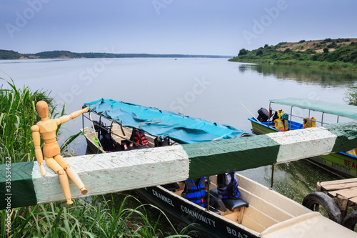 Little wooden manikin pointing to a boat in the Kazinga Channel, Lake Edward, Uganda, Africa photo