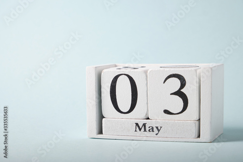 Wooden calendar on a blue background with the date of May 3