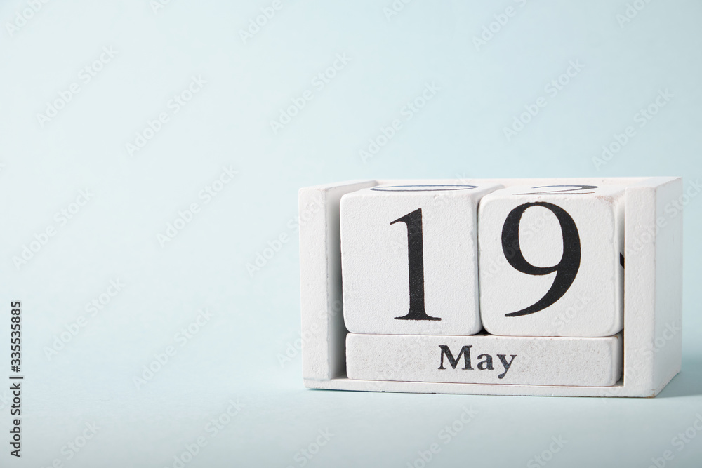 Wooden calendar on a blue background with the date of May 19 Wooden calendar on a blue background with the date of May 19