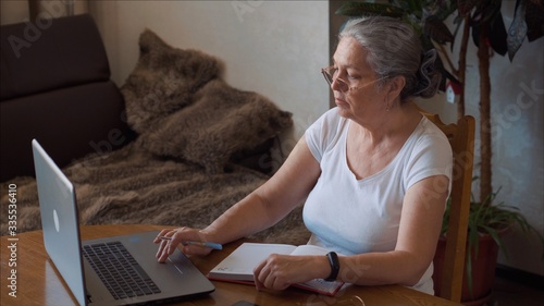 Coronavirus. Aged woman take notes at home. Woman in quarantine for coronavirus