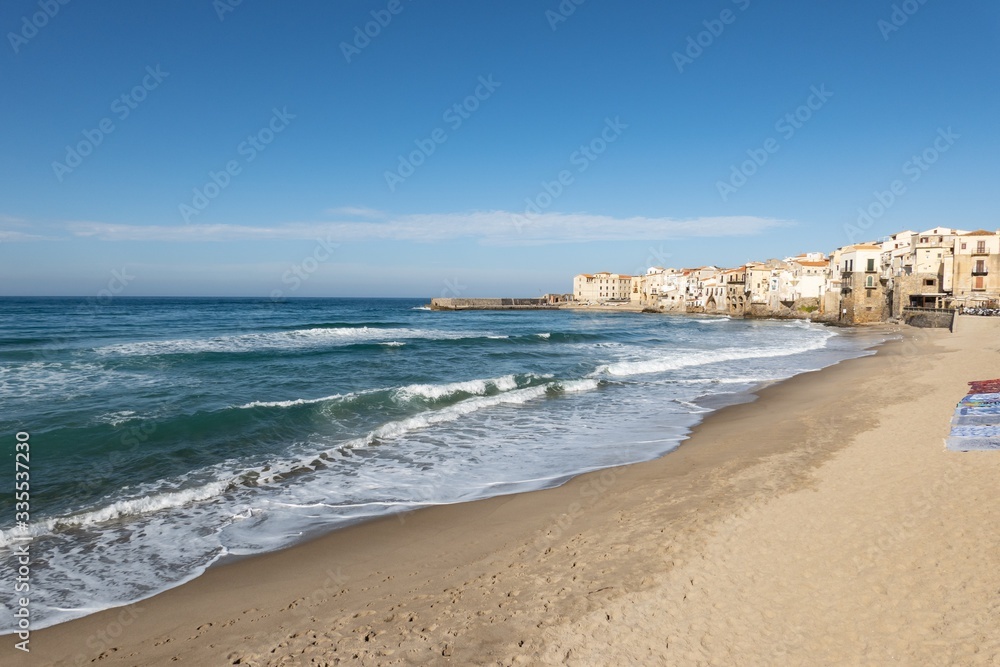 Empty sandy beach in Cefalu with a nice blue sky and sea waves