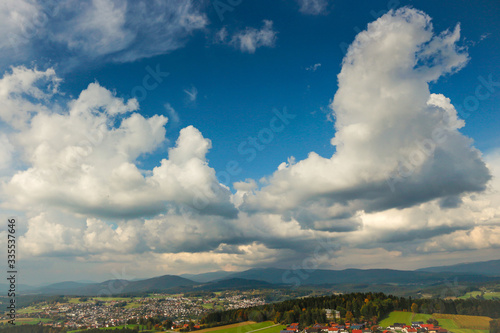 Urlaub in Deutschland: Blick über den Bayerischen Wald bei Bischofsmais mit sommerlichem Kumuluswolken-Himmel