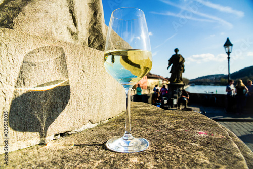 Weißweinglas mit Lichtreflektion und Schattenfall auf einem Denkmal: Beim Brückenschoppen auf der Alten Mainbrücke in Würzburg
