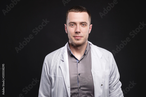 Portrait of a young intern doctor. A man is standing in a photo studio. Making a diagnosis. Studio portrait
