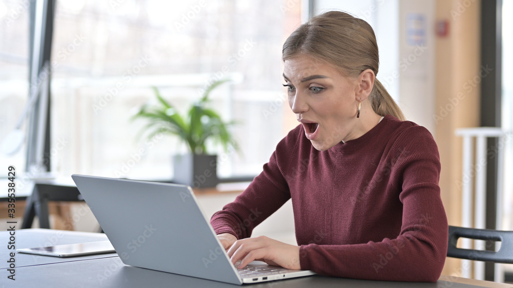 Happy Young Woman Surprised by Results on Laptop Happy Young Woman Surprised by Results on Laptop