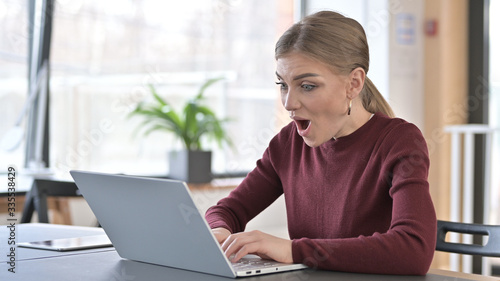 Happy Young Woman Surprised by Results on Laptop