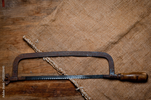 Old vintage metal hacksaw of the last century extracted from the chest in the workshop of grandfather. Background for craftsmanship and manual labor.