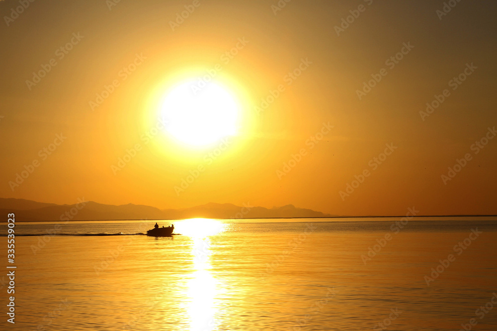 beautiful Golden dawn on the sea, a boat sails on the sea at dawn, a Golden path from the sun on the sea