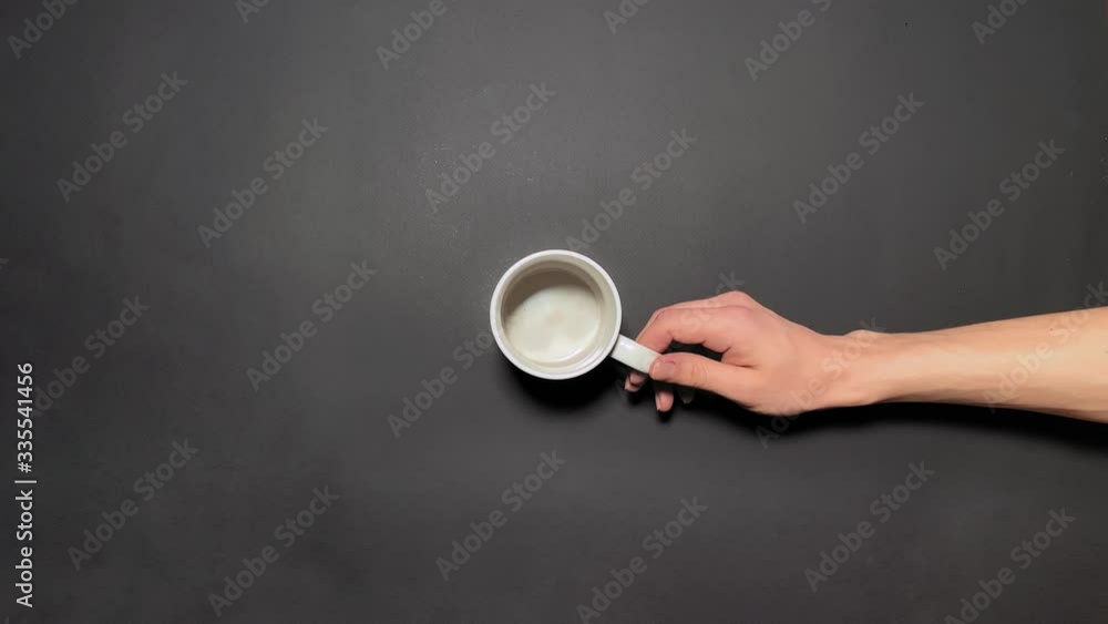 Top view. Hand rotates the mug and it is filling with coffee or tea. On grey background. Concept of time coffee, energy, advertisement, power, systems. Cup of coffee 4k stock footages Top view. Hand rotates the mug and it is filling with coffee or tea. On grey background. Concept of time coffee, energy, advertisement, power, systems. Cup of coffee 4k stock footages