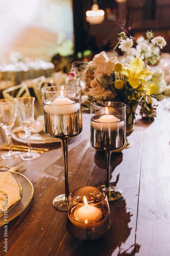 Naklejka premium Wedding banquet. Table setting. Banquet tables are decorated with compositions of yellow flowers and lemons, on the tables are plates with napkins, glasses, candles and cutlery