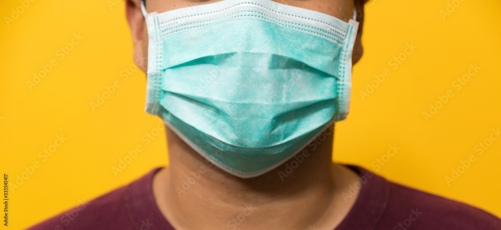 Close up young asian man wearing protection face mask against coronavirus on yellow background. Close up young asian man wearing protection face mask against coronavirus on yellow background.