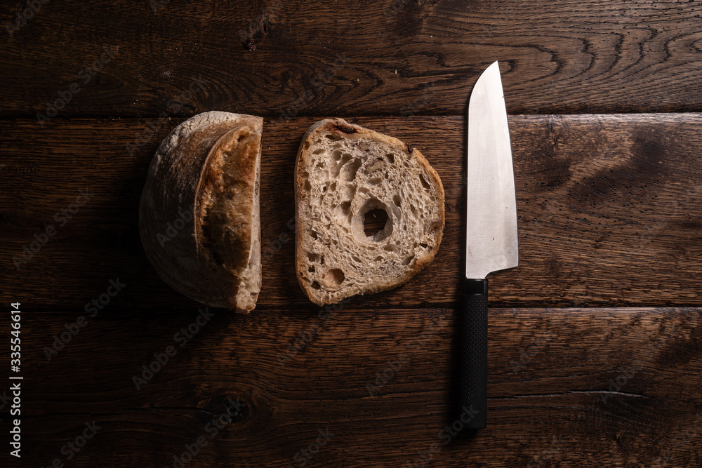Zdjęcie bochenka chleba i noża na drewnianym, naturalnym stole - obrazy, fototapety, plakaty 
