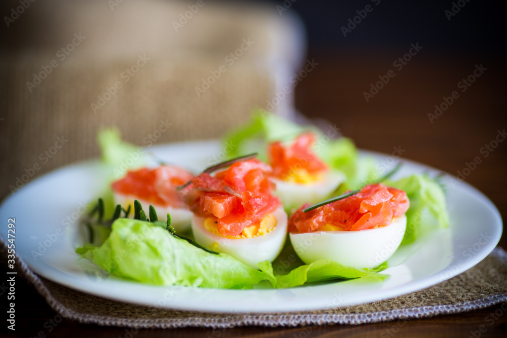 boiled eggs with salted red fish and salad leaves