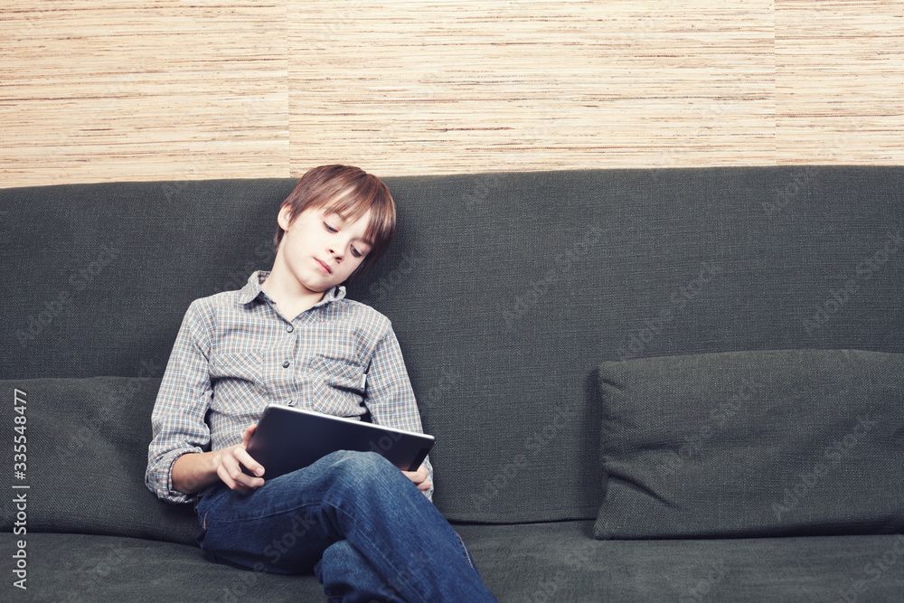 Frustrated boy with tablet confined at home during isolation Frustrated boy with tablet confined at home during isolation