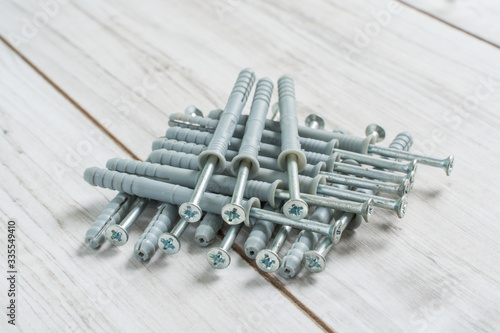 Group of Dowels and Nails on wooden background. Dowels for fastening in concrete. Stock photo.