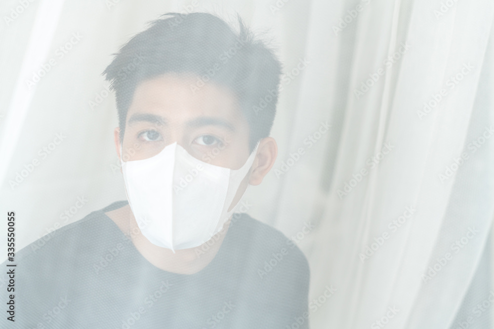 Asian man wearing Face Mask to protect feeling sick headache and cough because of Coronavirus covid-19 in quarantine room , Quarantine yourself to protect spread Covid-19 Coronavirus Asian man wearing Face Mask to protect feeling sick headache and cough because of Coronavirus covid-19 in quarantine room , Quarantine yourself to protect spread Covid-19 Coronavirus