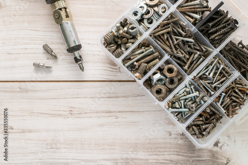 Screws, bolts, nuts and other carpenter stuff in a plastic toolbox (hardware organizer) with a screwdriver. Flat lay top view with copyspace for text. Stock photo.