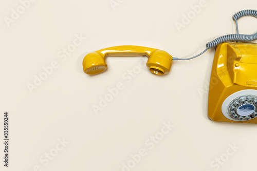 Old fashioned handset on beige color background. Modern retro style of rotary telephone. photo