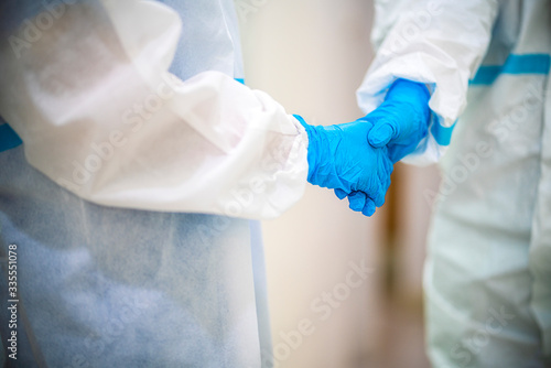 two doctor wearing ppe suit and face mask in hospital hand shaking after patient get well. Corona virus, Covid-19, virus outbreak, medical mask, hospital, quarantine or virus outbreak concept