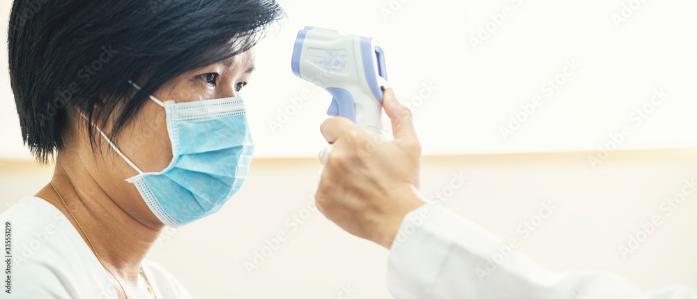 Fototapeta premium Banner of doctor check Asian woman body temperature using infrared forehead thermometer (thermometer gun) for virus symptom at hospital. Corona virus, Covid-19, quarantine or virus outbreak concept