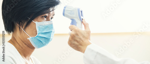 Banner of doctor check Asian woman body temperature using infrared forehead thermometer (thermometer gun) for virus symptom at hospital. Corona virus, Covid-19, quarantine or virus outbreak concept