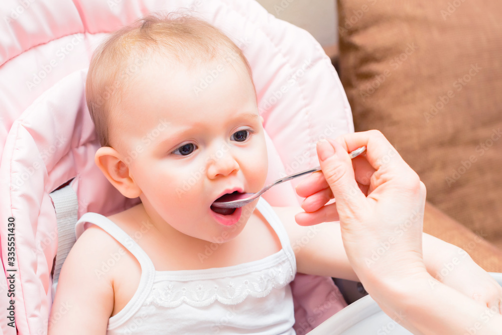 Feeding cute baby girl in pram with spoon Feeding cute baby girl in pram with spoon