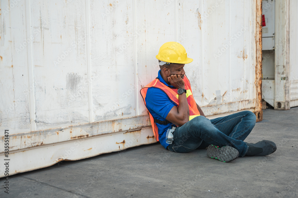 Tired  depressed black foreman worker working at Container cargo harbor to loading containers. African dock male staff fall asleep for Logistics import export shipping concept.