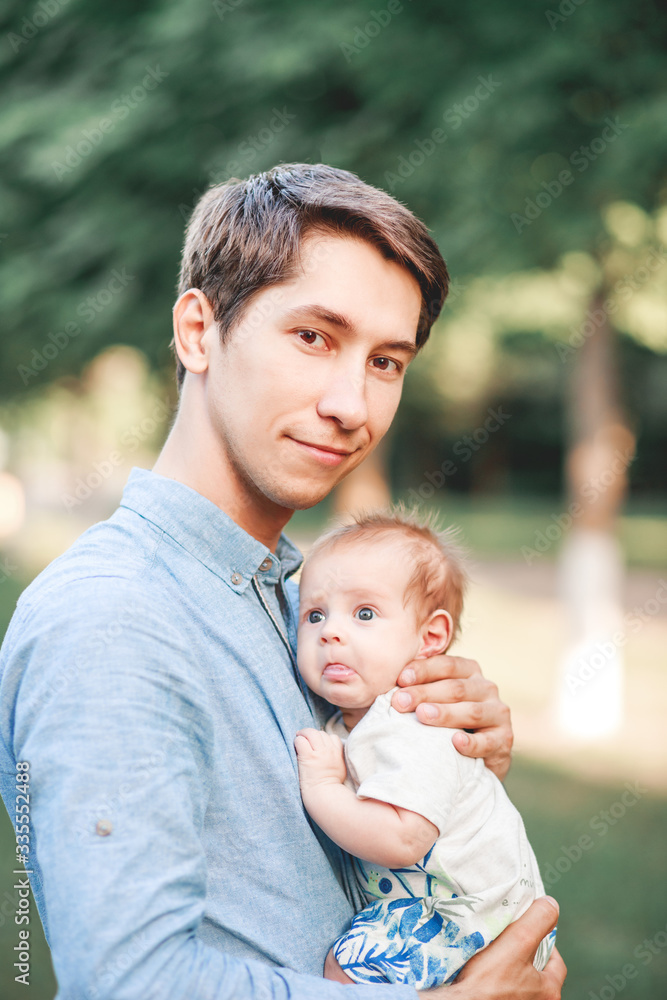 Fototapeta premium A father holds his son in his arms, in a garden