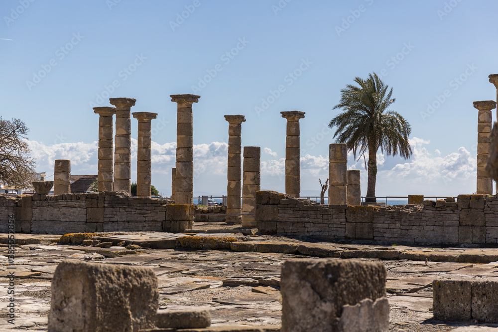 Roman archaeological site in which we can see ancient stone buildings with numerous columns facing the sea